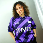 Person wearing a purple sports jersey with 'TOYOS' branding against a neutral background