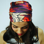 Woman wearing a colorful headscarf with a white tank top featuring 'TOYOS' branding.